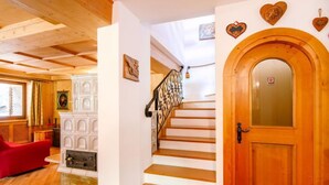 Un interior de madera con una escalera, una silla roja y una puerta con un panel de vidrio.