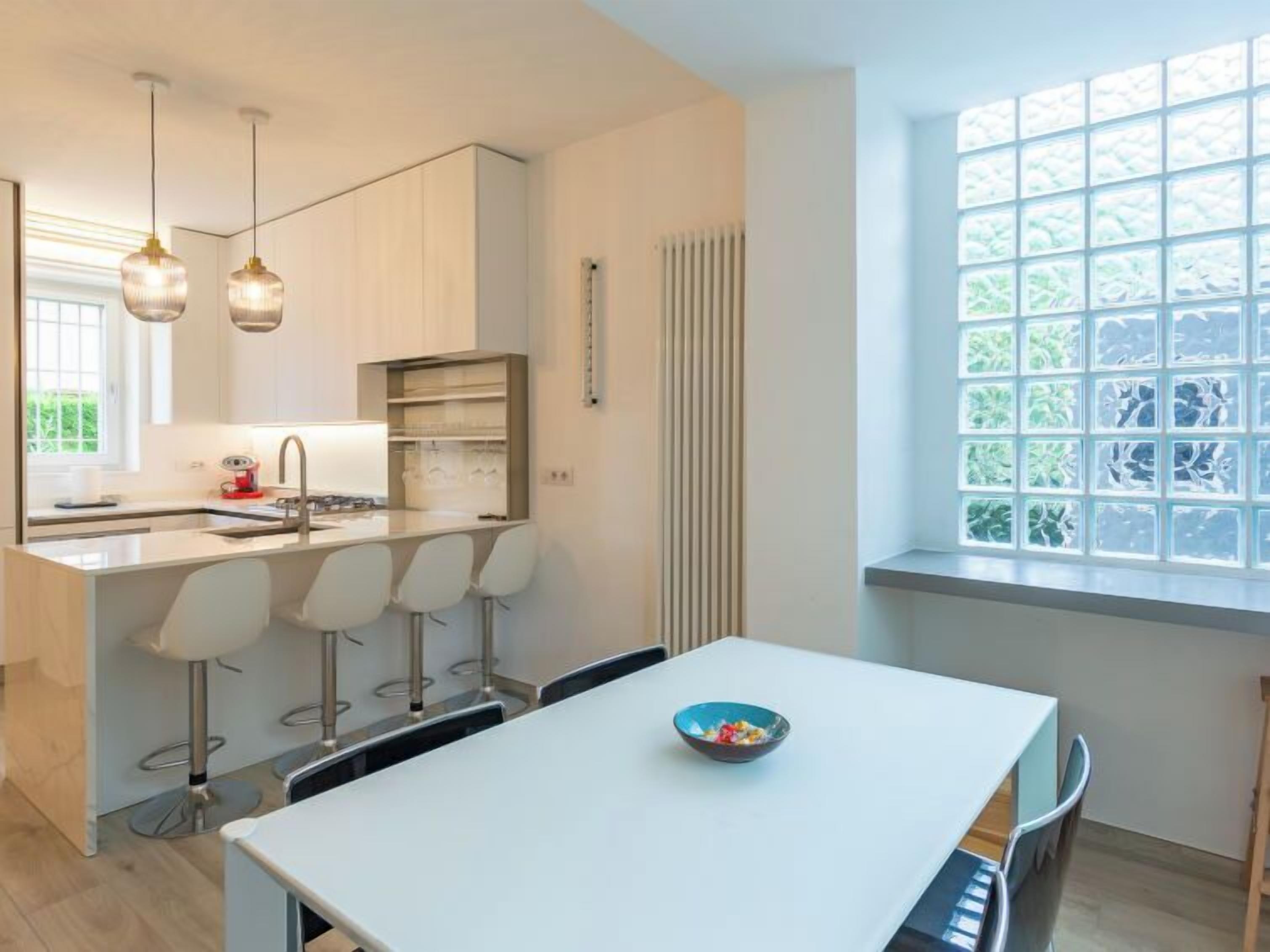 A modern kitchen with a central island, bar stools, and pendant lighting.