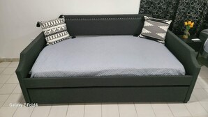 A Galaxy Z Fold4 sofa with patterned pillows, a vase with flowers, and a patterned curtain in a room with white walls and tiled floor. - Scenic Views in Paradise Resorts (Canovanas)