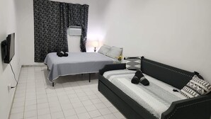 A bedroom with a bed, a sofa, a TV, and a window with patterned curtains. - Scenic Views in Paradise Resorts (Canovanas)