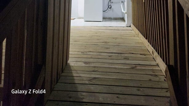 A wooden deck leading to a white interior with a refrigerator and a washing machine. - Scenic Views in Paradise Resorts (Canovanas)