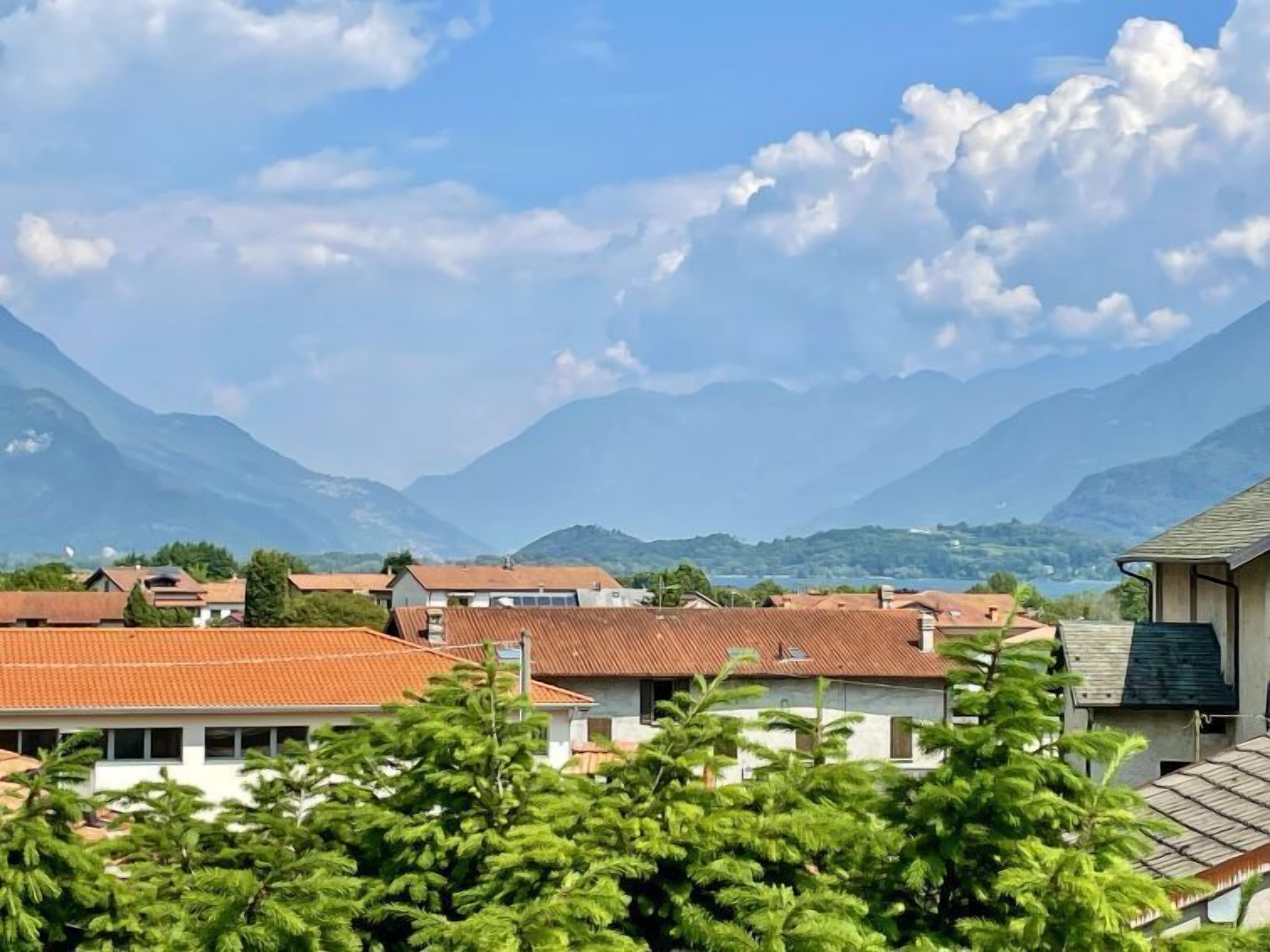 Un barrio residencial con casas, una cadena montañosa al fondo y un cielo despejado.