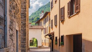 A narrow cobblestone street flanked by historic stone and plaster buildings with arched doorways and shuttered windows. - Il sogno di Elvira by Interhome (Domaso)