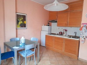 Enjoy meals in this cozy kitchen and dining area, featuring a glass table and comfortable seating.