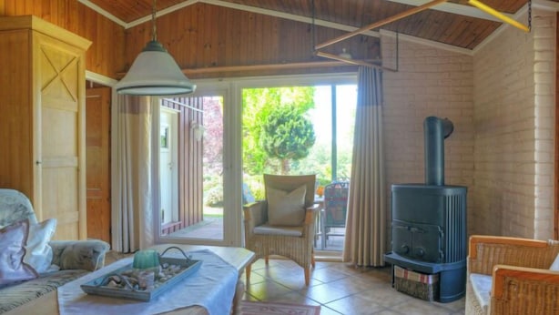 Ein gemütliches Zimmer mit Bett, Tisch mit Tablett, Stuhl, Kamin und Blick ins Freie.