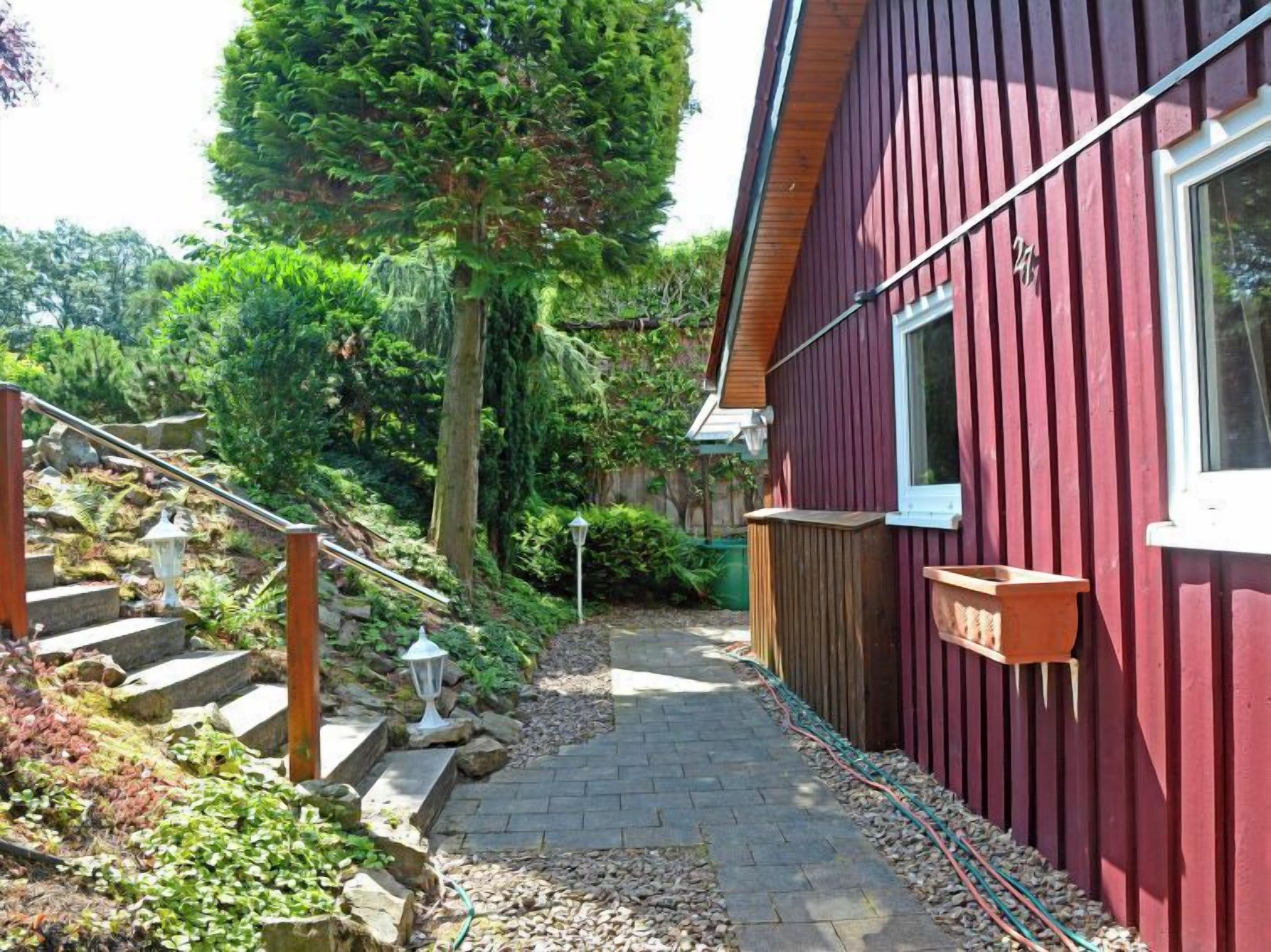 A red wooden house with a stone staircase leading to a wooden deck.