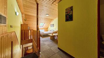 A wooden interior with a staircase, a bed, and a small table.