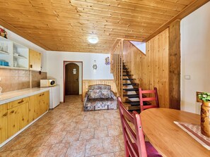 A wooden interior with a kitchen, a dining area, and a staircase.