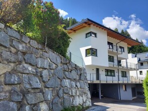 A modern multi-story building with a stone retaining wall, balconies, and a clear sky. - Bergblick by Interhome (See)