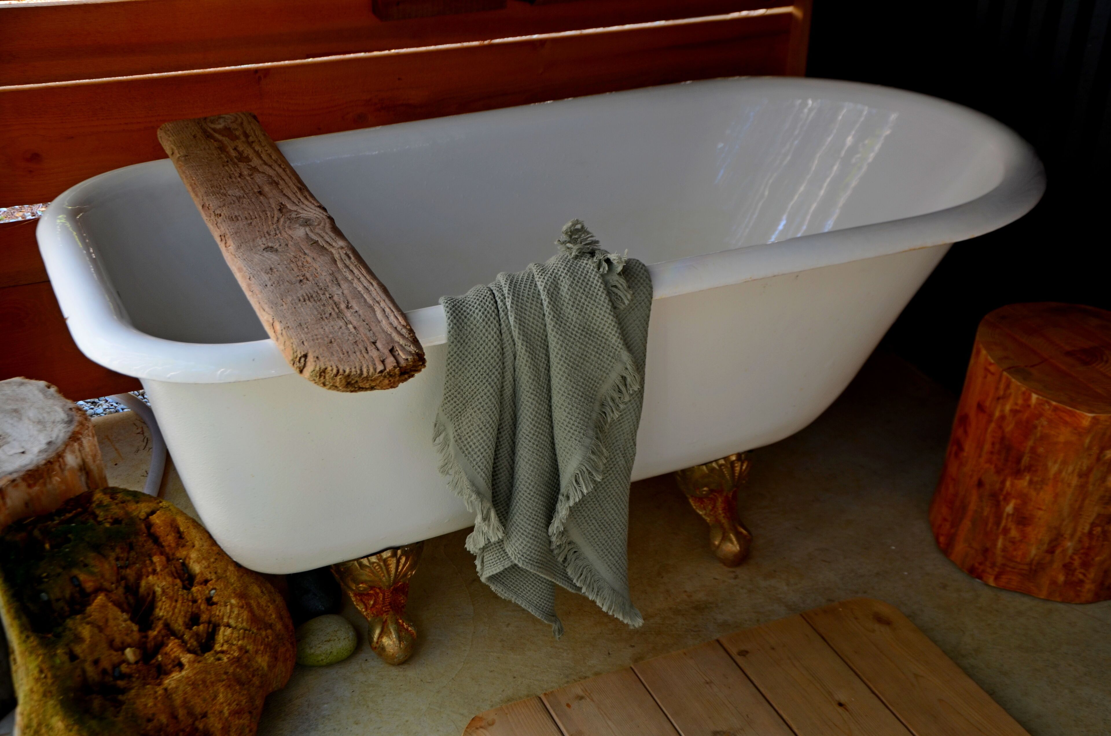 A bathtub with a wooden log and a green towel.
