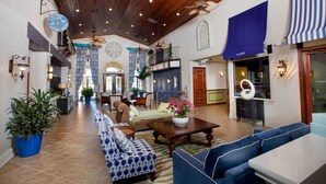 Eine geräumige Lobby mit hoher Decke, Holzbalken und einer Sitzecke mit blau-weißen Sofas.