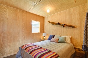 Una stanza accogliente in legno con un letto, una finestra e un modellino di aereo appeso al muro.