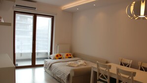 Een slaapkamer met een bed, een bureau en een stoel. Er is een raam en een radiator.