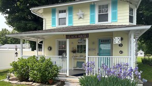 A two-story house with a porch, a sign reading "Beach House," and a welcome sign. - Beautiful old style beach cottage 
Walk to beach/ restaurants 
Center of town (Branford)