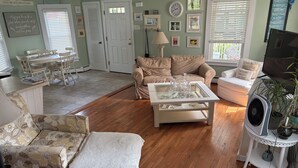 A cozy living room with a floral sofa, a glass-top coffee table, and a beige armchair. - Beautiful old style beach cottage 
Walk to beach/ restaurants 
Center of town (Branford)