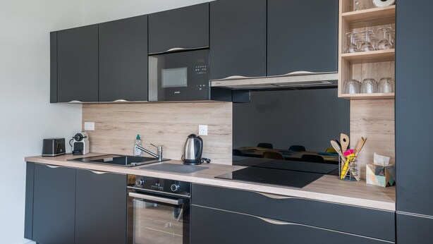 A modern kitchen with dark cabinetry, a wooden countertop, a built-in oven, and a microwave. - A bright cocoon for a pleasant stay in Arcachon (Arcachon)