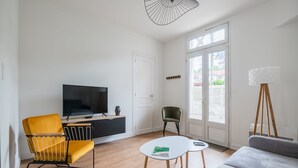 A modern living room with a sofa, a yellow chair, a television, and a floor lamp. - A bright cocoon for a pleasant stay in Arcachon (Arcachon)