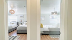 Un dormitorio con dos camas, piso de madera y una ventana con persianas.