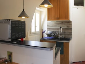 A kitchen with a built-in microwave, a sink, and wooden cabinets.