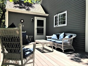 A covered outdoor seating area with wicker furniture and a small table.