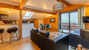 Ein gemütliches Blockhaus-Interieur mit Essbereich, einer Couch und einem großen Fenster mit Blick ins Freie.
