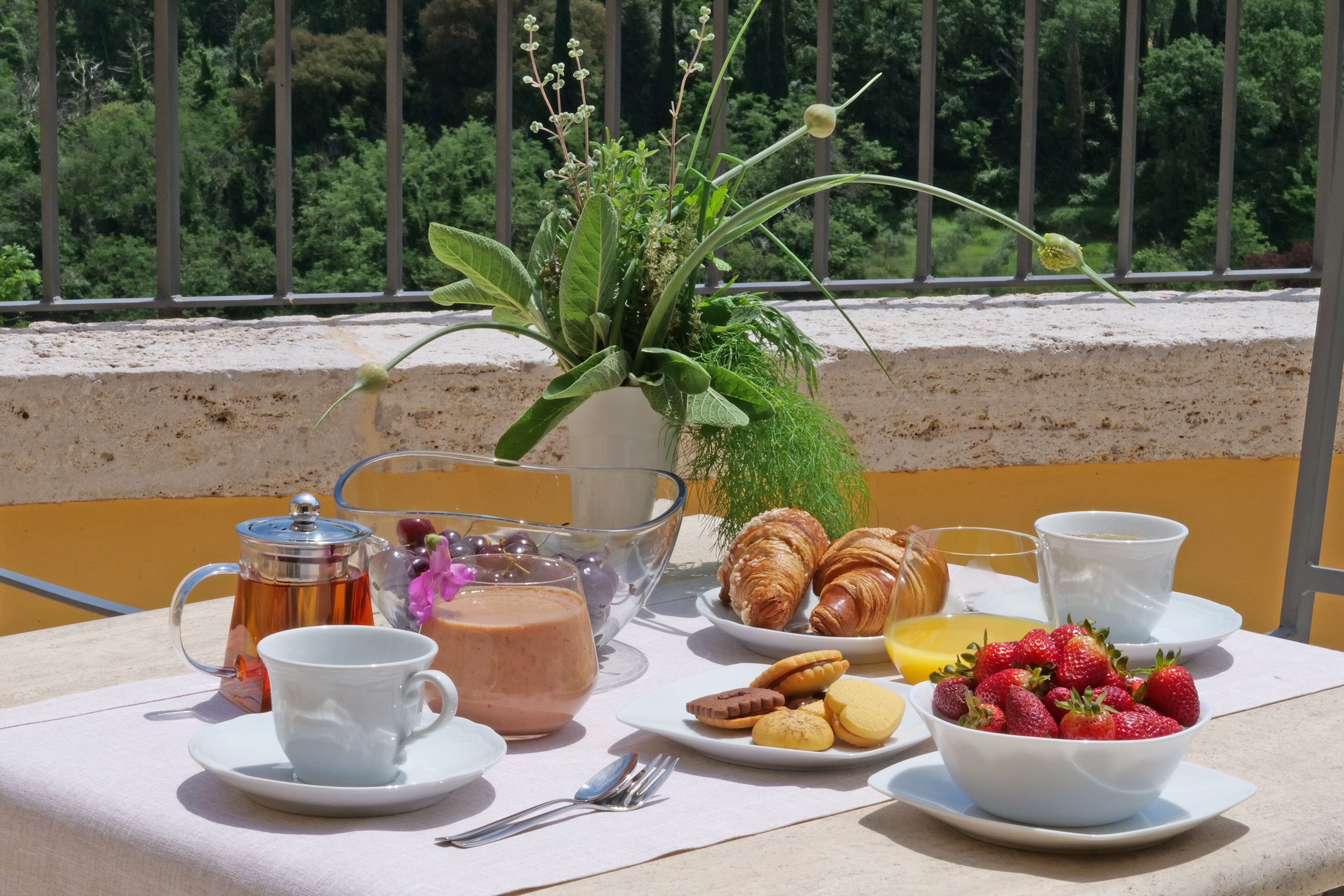 A table set with breakfast items, including croissants, strawberries, and a coffee pot.