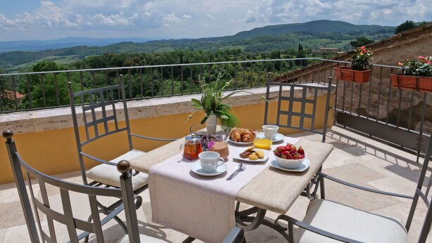 Una terraza con una mesa lista para el desayuno, con vistas a un paisaje pintoresco.