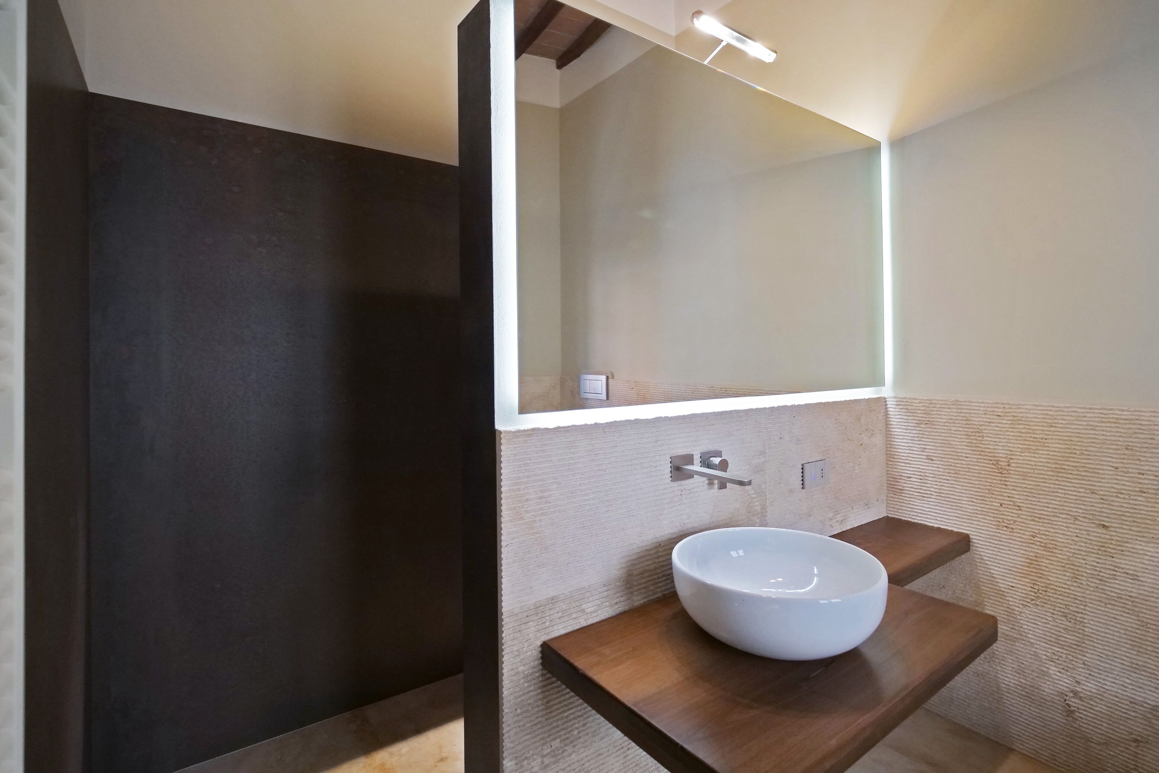 Casa de banho moderna com um espelho grande, toucador de madeira e lavatório branco.