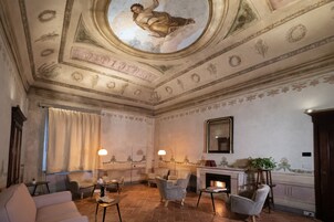 A room with a fireplace, seating area, and a decorative ceiling.