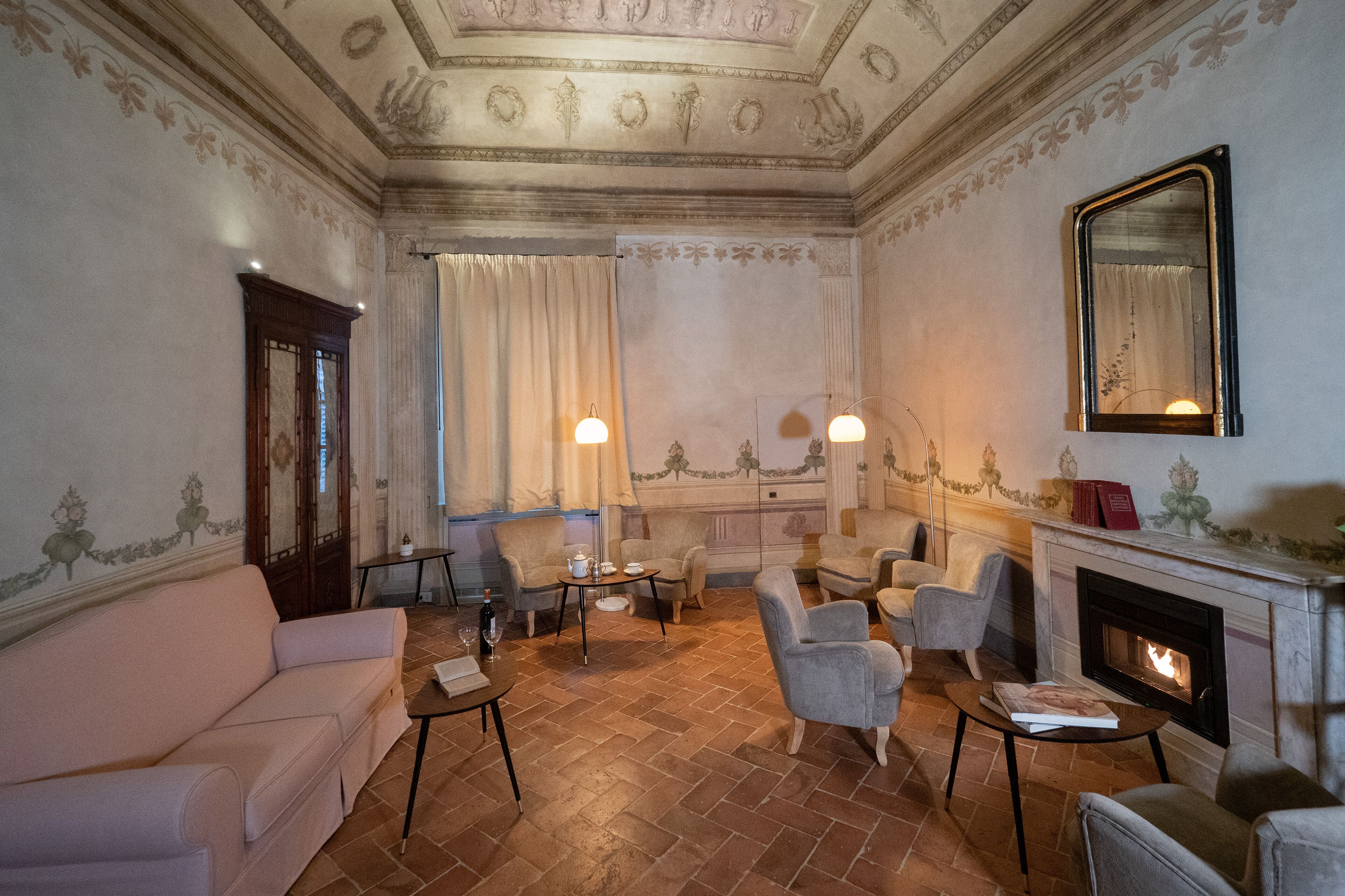 A room with a fireplace, a sofa, armchairs, and a table with a book.