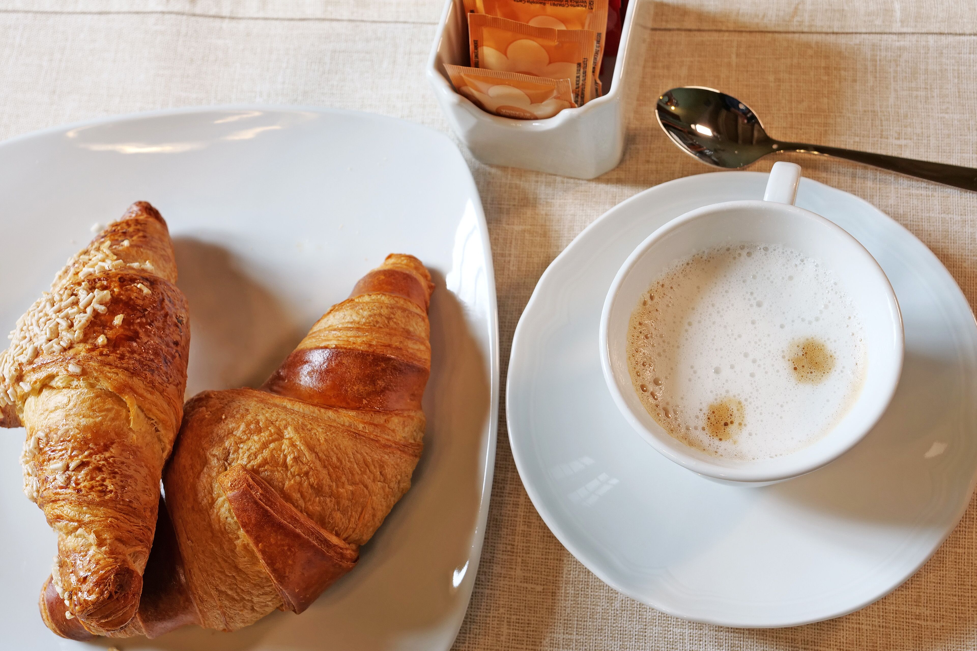 A plate with two croissants and a cup of coffee on a table.