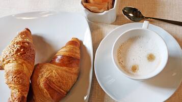 A plate with two croissants and a cup of coffee on a table.