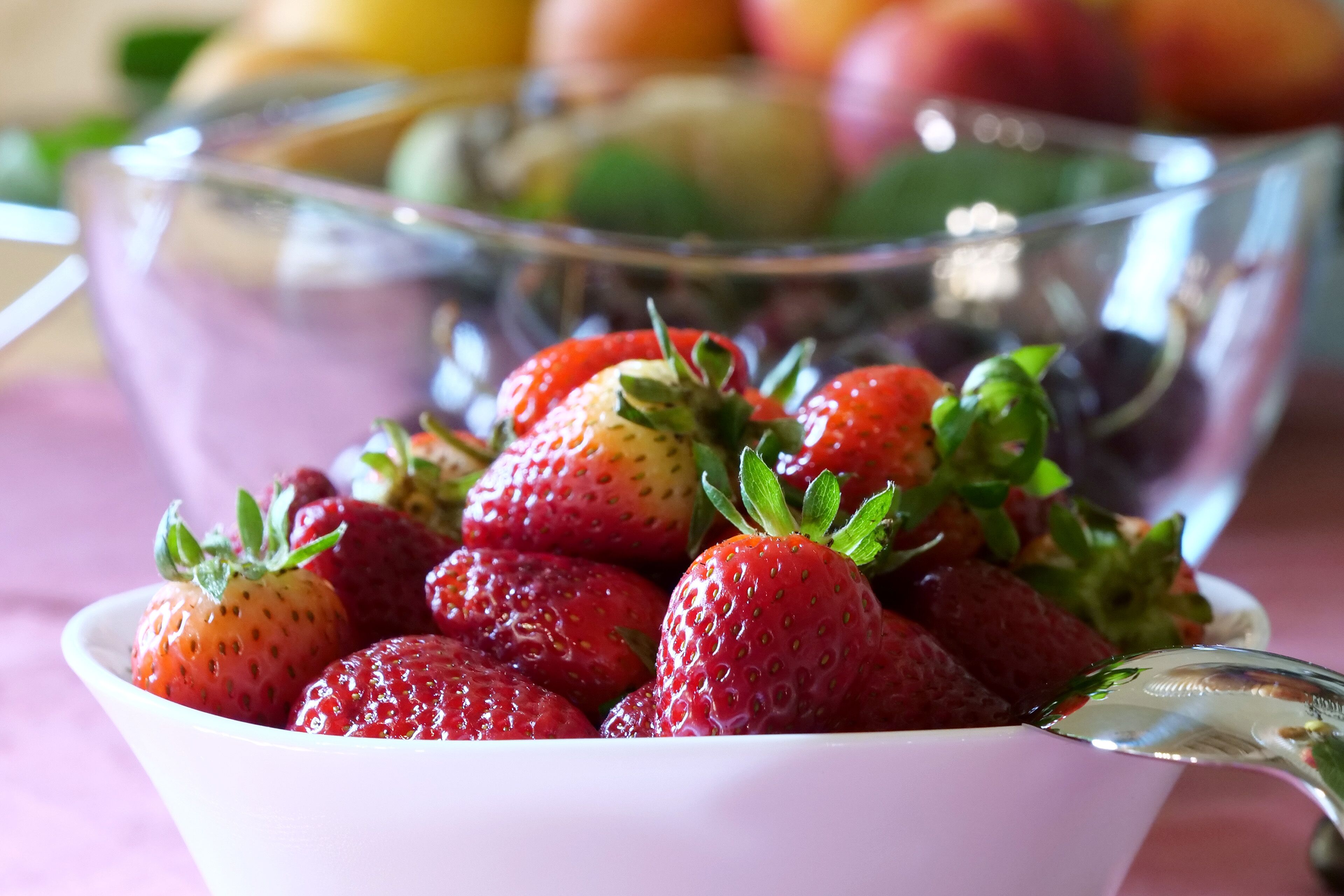 A bowl of fresh strawberries with a spoon.