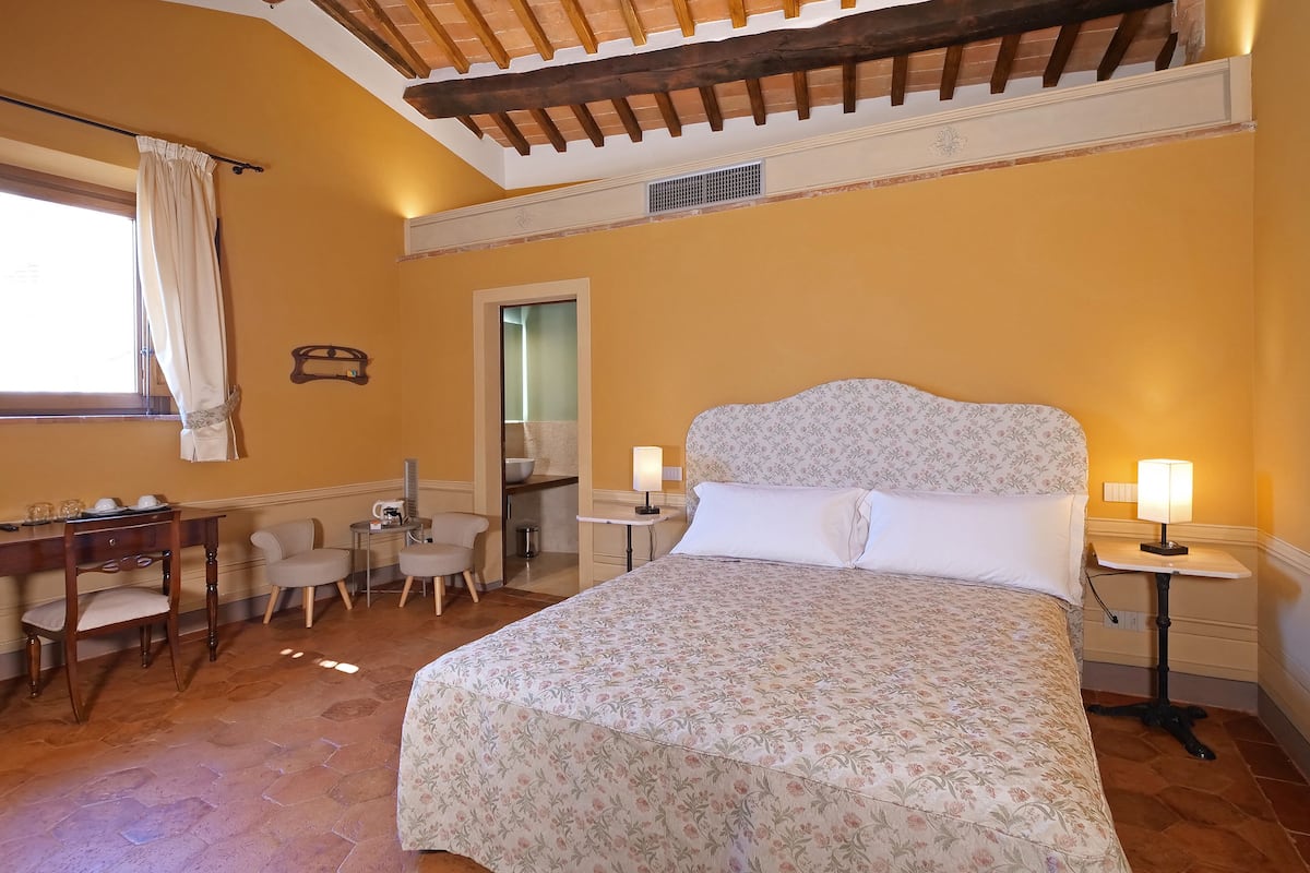 Une chambre à coucher comprenant un lit, deux tables de chevet avec des lampes, un bureau avec une chaise et une petite salle de bain.