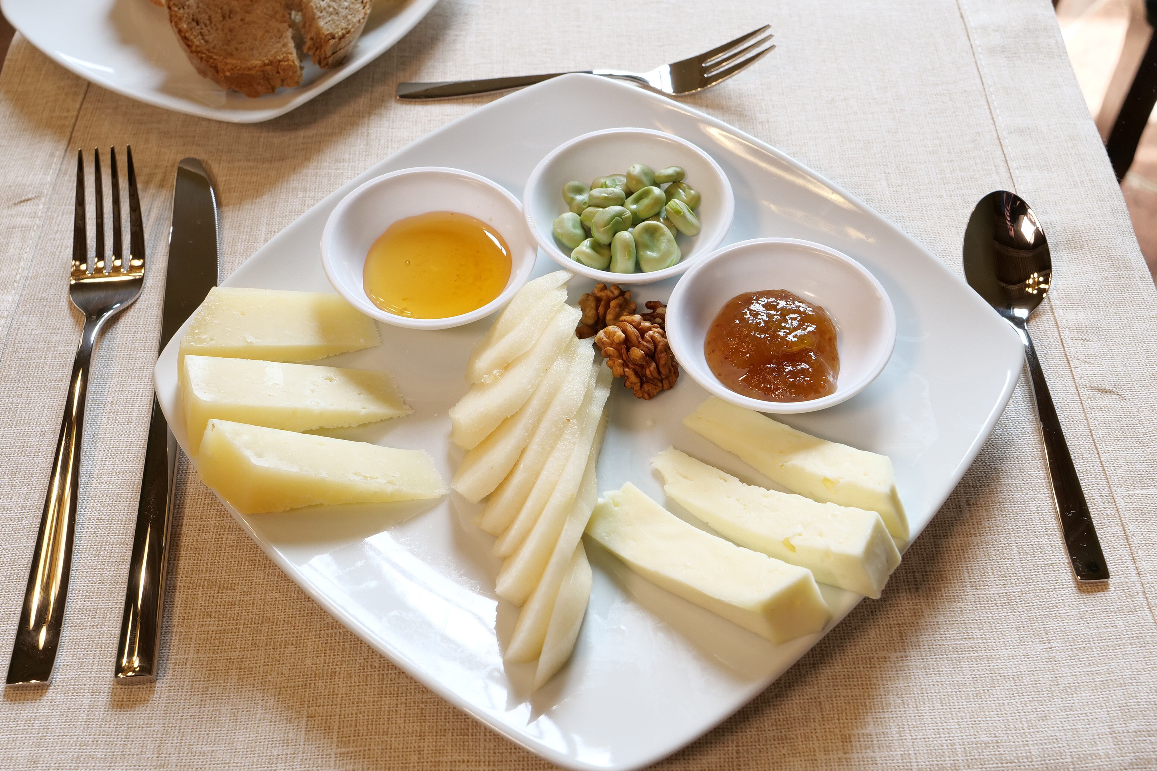 Un plato con queso, frutos secos y dos tipos de salsa.
