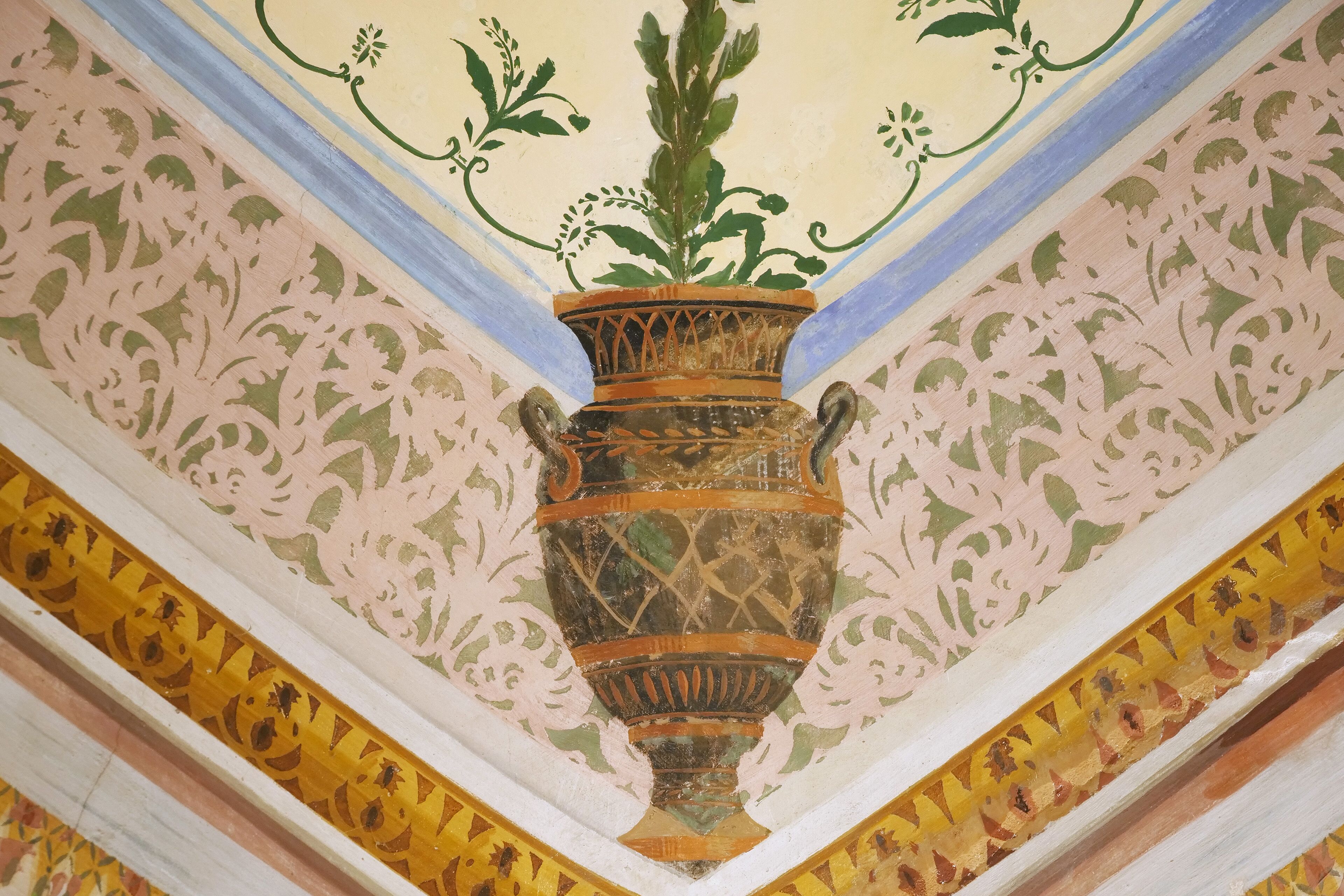 Eine Decke mit einer zentralen dekorativen Vase, floralen Mustern und einer geometrischen Bordüre.