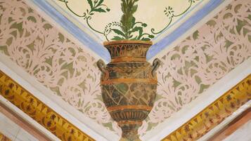 Eine Decke mit einer zentralen dekorativen Vase, floralen Mustern und einer geometrischen Bordüre.