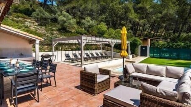 Un área de patio al aire libre con una barbacoa, asientos y una piscina.