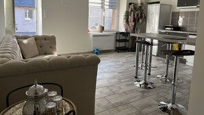 A modern living room with a sofa and a dining area with bar stools.