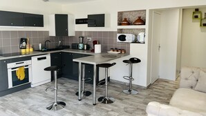 A modern kitchen with grey cabinets, a black countertop, and three bar stools.