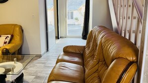 A modern living room with a leather sofa, a glass coffee table, and a yellow armchair.