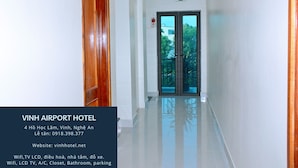 Pasillo de hotel con una puerta de madera, una puerta de cristal con vistas y un cartel que indica una salida.