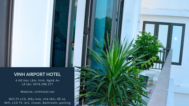 Un edificio moderno con amplios ventanales y puertas de vidrio, un balcón con plantas en macetas y un letrero que indica HOTEL VINH AIRPORT.