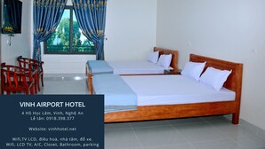 Habitación de hotel con dos camas, un televisor y un ventilador.