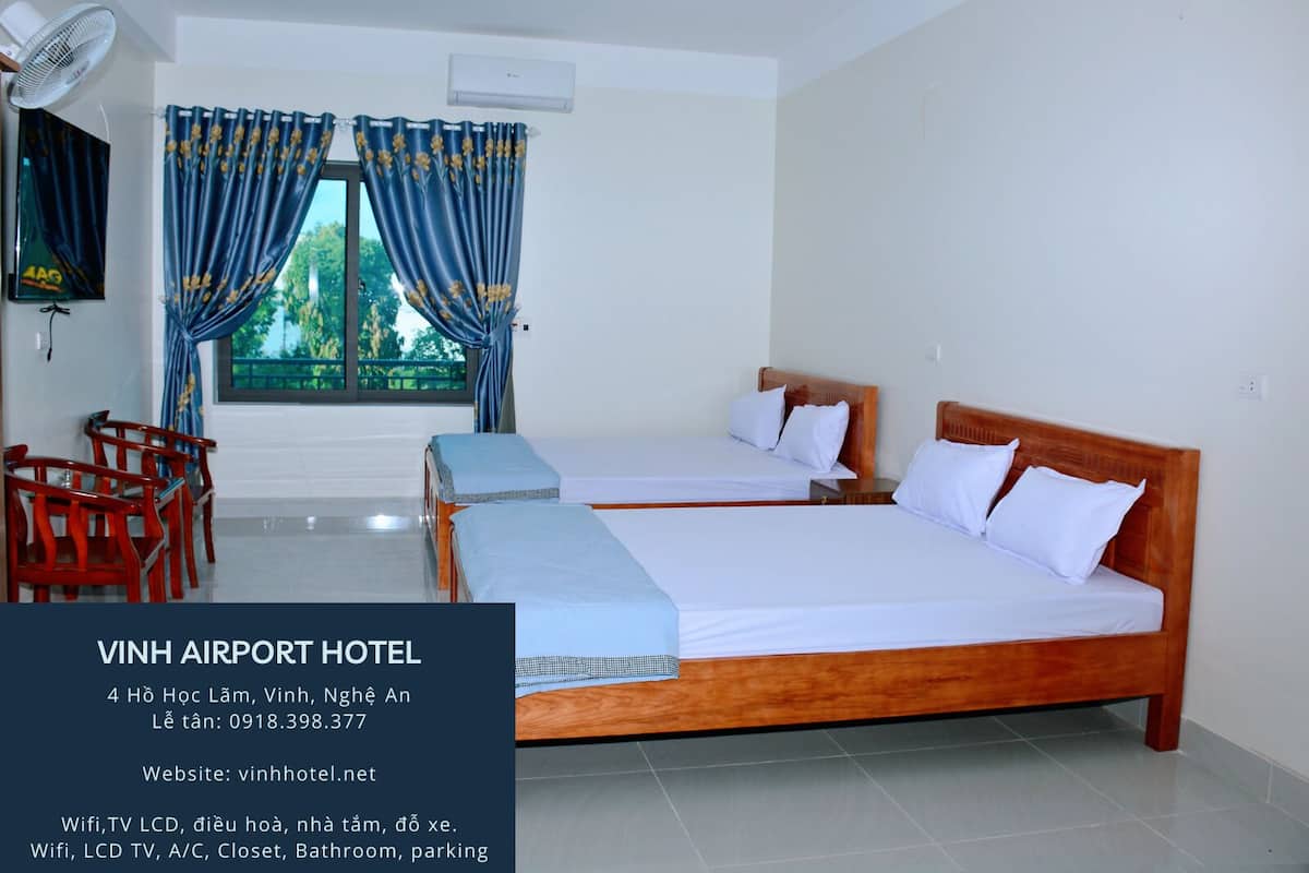 A hotel room with two beds, a TV, and a fan.