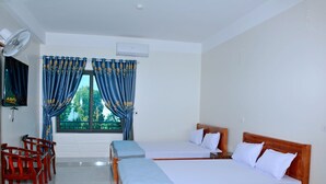 Een hotelkamer met twee bedden, een televisie en een ventilator.