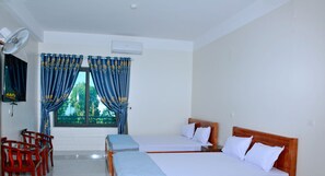 Een hotelkamer met twee bedden, een televisie en een ventilator.