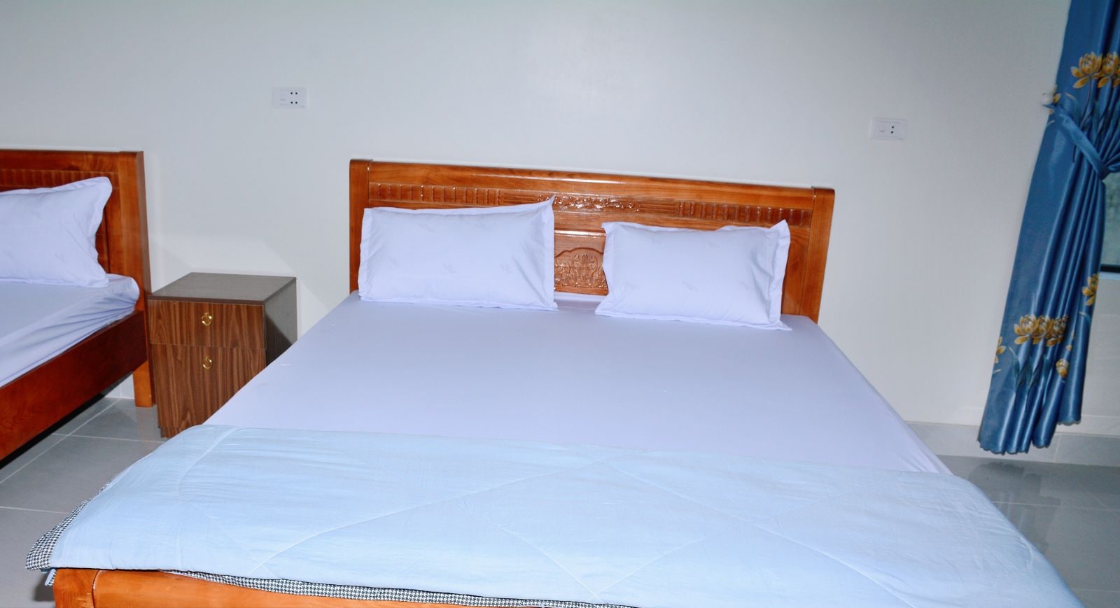 A hotel room with a large bed, a wooden headboard, and a nightstand.