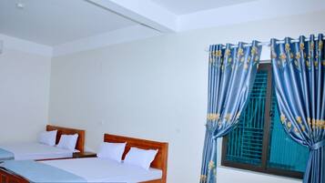 Quarto de hotel com duas camas, uma janela com cortinas azuis e design moderno e limpo.