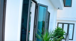 Ein modernes Gebäude mit großen Glasüren und -fenstern, einem Balkon mit Blumentöpfen und einem Schild für VINH AIRPORT HOTEL.